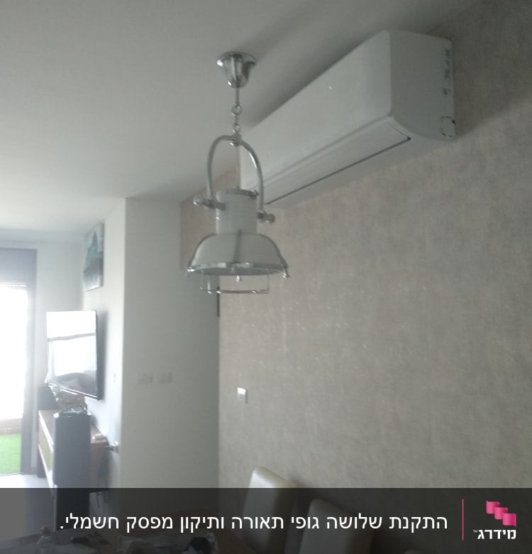 מזגן מותקן על קיר בחדר עם מנורה תלויה